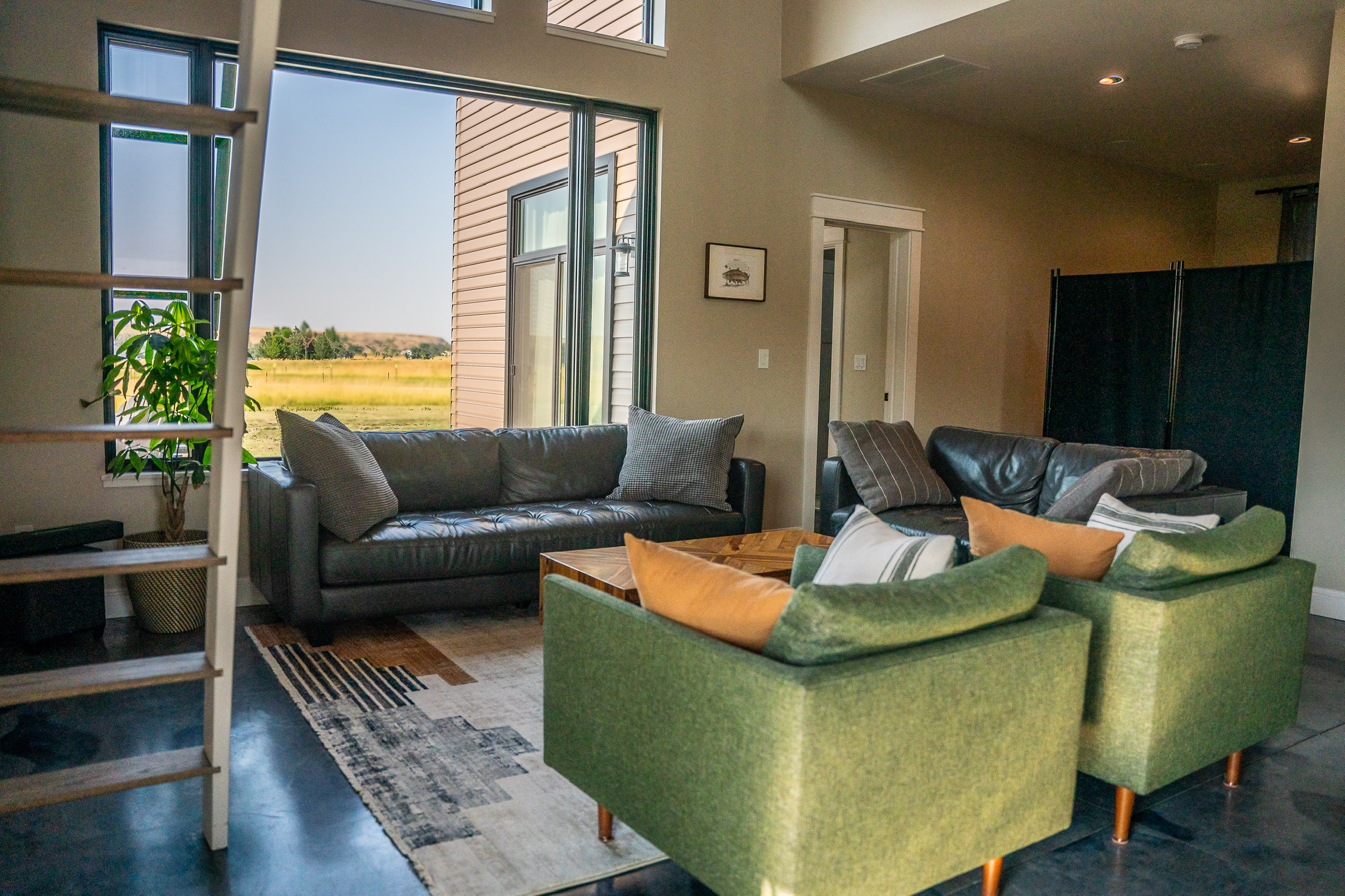 Living room with leather sofa and green accent chairs at 3 Mile Cabin