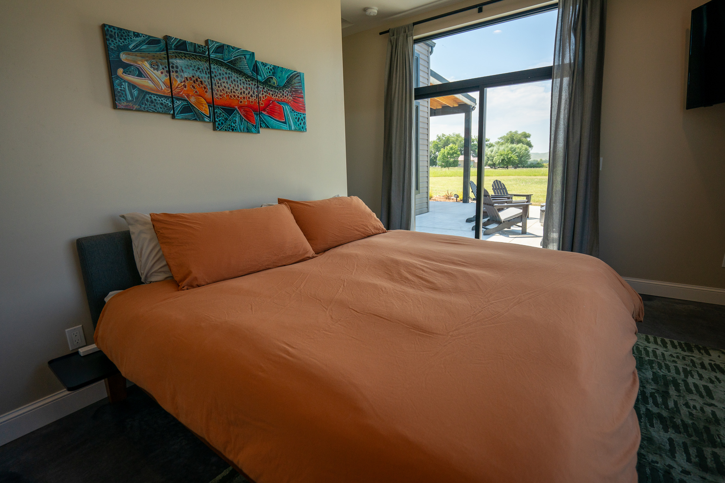 Master bedroom with king bed and trout art at 3 Mile Cabin